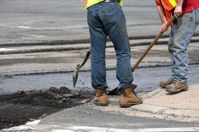 two men working in streetworks on the road with shovels