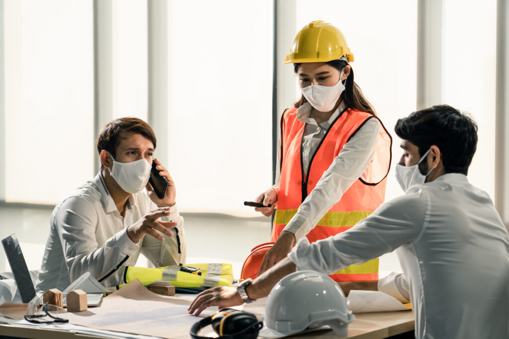 Construction professionals discussing workplace safety procedures during power tools training session in an office environment.